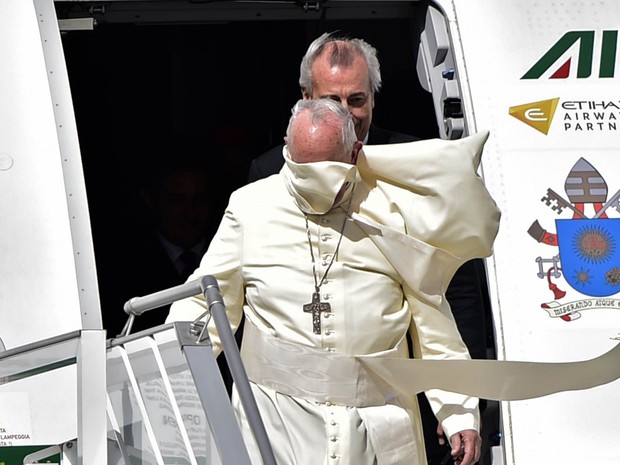 O vento ergue parte das vestes do Papa Francisco e cobre seu rosto ao desembarcar no aeroporto internacional Mariscal Sucre, em Quito, Equador.