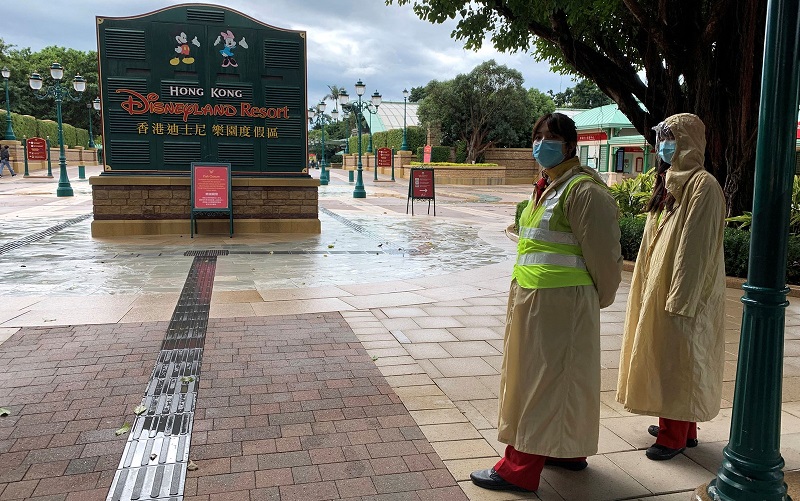 Funcionários usando máscaras são vistos do lado de fora da Disneyland Hong Kong, fechada, no domingo (26) — Foto: Reuters/James Pomfret