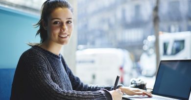 Portrait of charming young student sitting in coworking space looking at camera while making researches browsing information on laptop computer with mock up screen connected to wireless internet