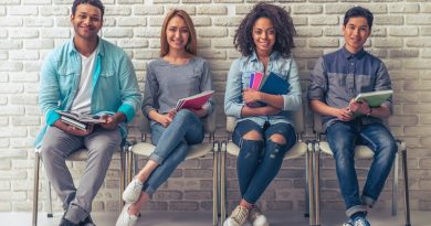 Young people of different nationalities are holding books and notebooks, looking at camera and smiling while waiting for interview