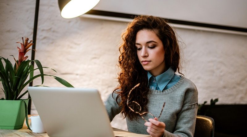 College student working on laptop at desk.