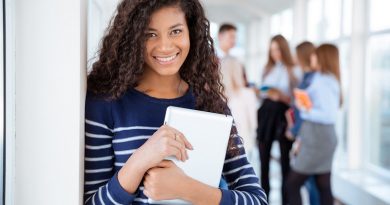 Portrait of a smiling female student standing in university hall with classmates on a background