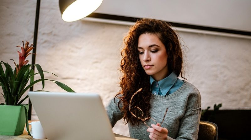 College student working on laptop at desk.