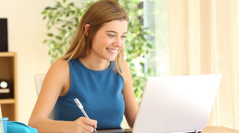 Beautiful student learning doing homework on line with a laptop in a desk at home with a window in the background