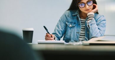 Happy female student sitting at college library and making notes. Woman studying at university library.