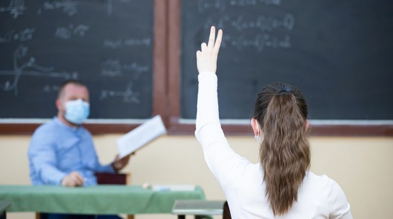 Teacher and his students wearing protective face mask in the classroom. Social distanting and classroom safety during coronavirus epidemic