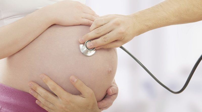pregnant woman and hand with stethoscope