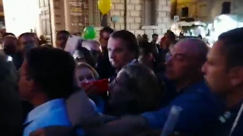 Jair Bolsonaro é cercado por agentes e comitiva durante passagem em Roma Crédito, Matheus Magenta/ BBC News Brasil Legenda da foto, 