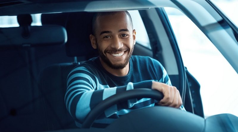 Driving gets him so excited. Shot of a handsome African man sitting in a car holding steering wheel smiling happily to the camera