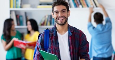 Lachender spanischer Student in der Uni-Bibliothek