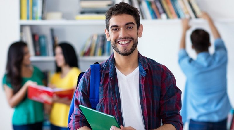 Lachender spanischer Student in der Uni-Bibliothek