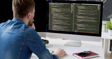 Rear view of concentrated thoughtful male programmer viewing computer language code on computer monitor while working on new program in modern office
