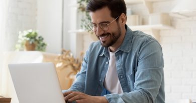 Smiling young man freelancer using laptop studying online working from home, happy casual millennial guy typing on pc notebook surfing internet looking at screen enjoying distant job sit at table