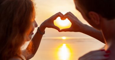 young sexu romantic couple in love happy on summer beach together having fun wearing swim suits showing heart sign on sundet