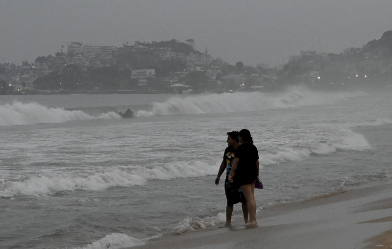 Moradores e turistas observavam o mar revolto na praia de Acapulco no final da tarde de terça-feira, horas antes da chegada do furacão monstro Otis ao balneário mexicano |(Foto: FRANCISCO ROBLES/AFP/METSUL METEOROLOGIA)