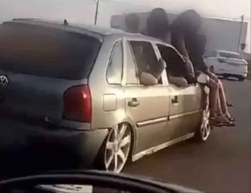 Imagem mostra carro circulando em avenida com cinco mulheres sentadas em capô em Aparecida de Goiânia — Foto: Reprodução/Redes Sociais