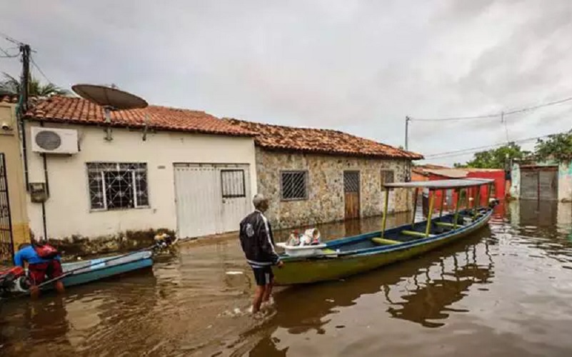 Foto divulgada em 2022 mostra um homem se movendo numa rua totalmente tomada por enchente, perto de uma pequena embarcação, no município de Marabá (Foto: Alex Ribeiro | Ag. Pará)