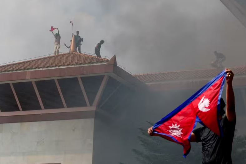 Manifestantes comemoram com bandeira do Nepal após entrar em complexo do Parlamento nepalês durante protesto contra o governo em 9 de setembro de 2025. — Foto: REUTERS/Adnan Abidi